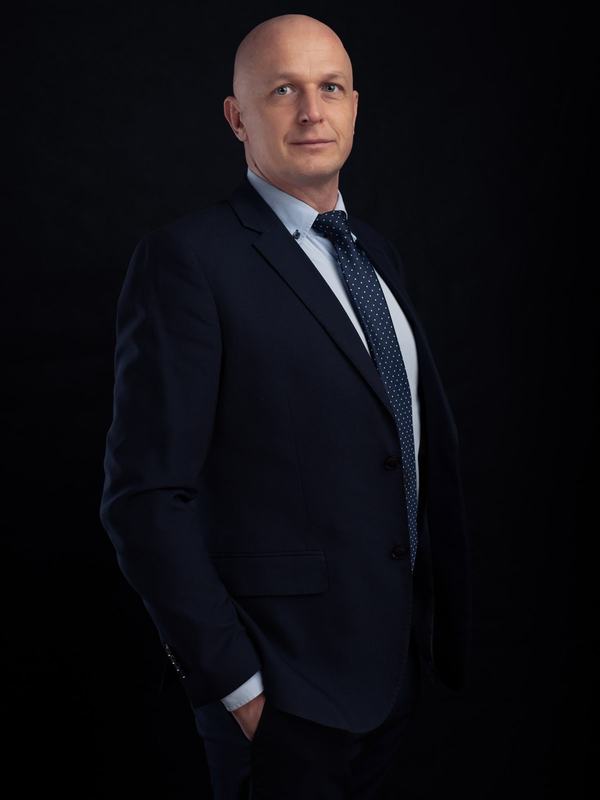 Dyrektor w garniturze z dłonią w kieszeni, portret menedżerski na czarnym tle