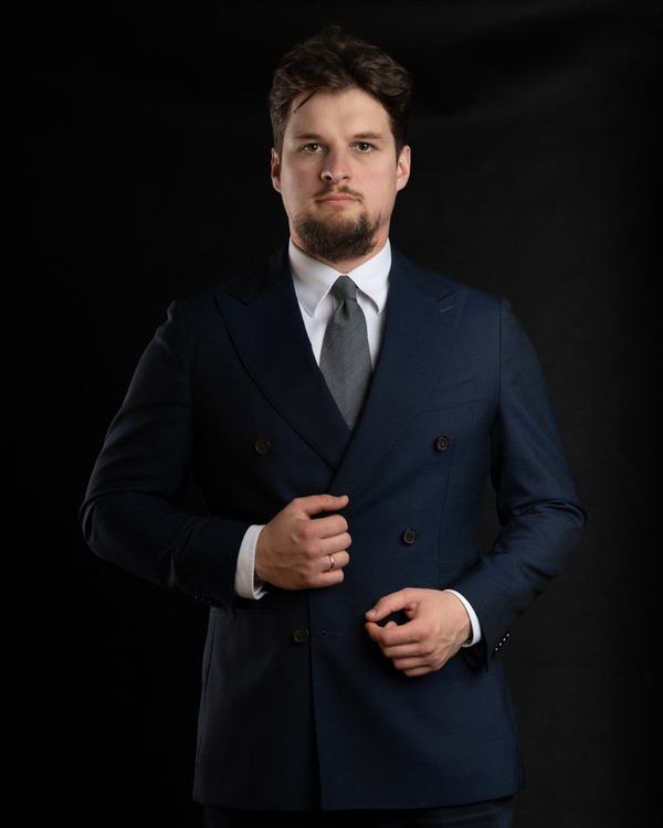 Portret biznesowy: adwokat w dwurzędowym granatowym garniturze na czarnym tle, kancelaria w Krakowie
