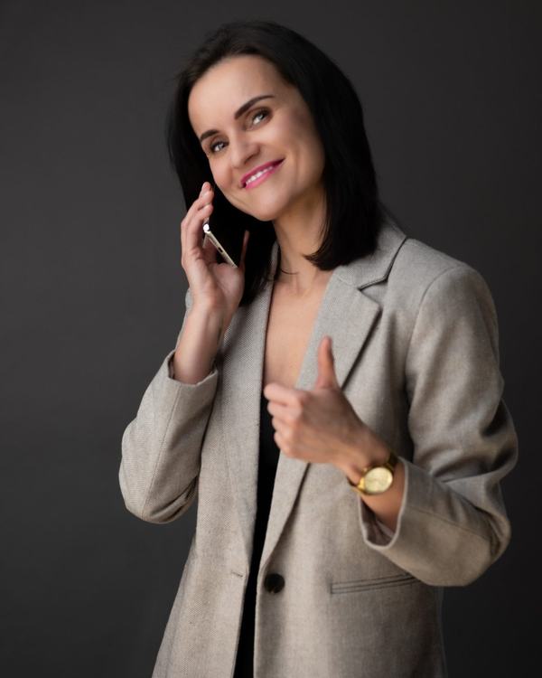 Portret biznesowy: agentka nieruchomości w beżowej marynarce rozmawia przez telefon