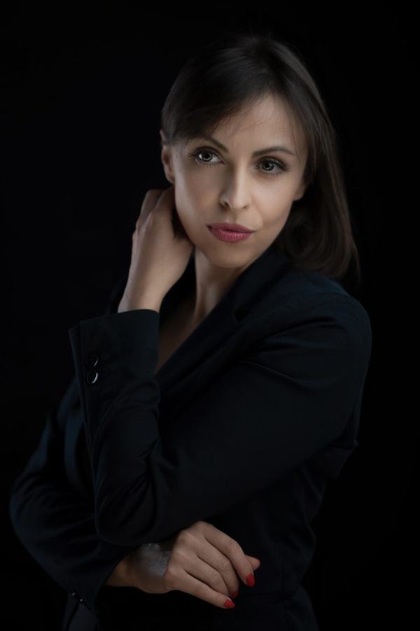 Portret biznesowy: brunetka w czarnej marynarce na ciemnym tle