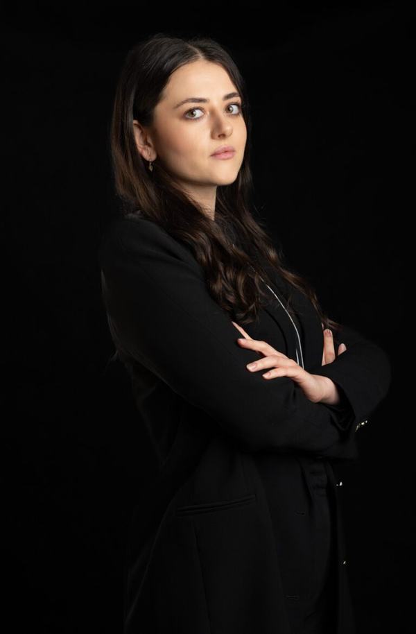 Portret biznesowy: brunetka w czarnej marynarce z rękami skrzyżowanymi