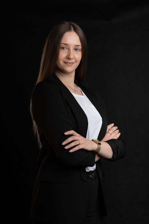 Portret biznesowy: młoda kobieta w czarnej marynarce z rękami skrzyżowanymi