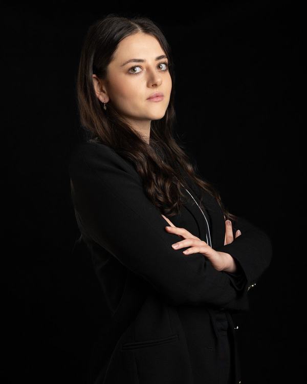Prawniczka w czarnej marynarce z rękami skrzyżowanymi, portret do strony kancelarii